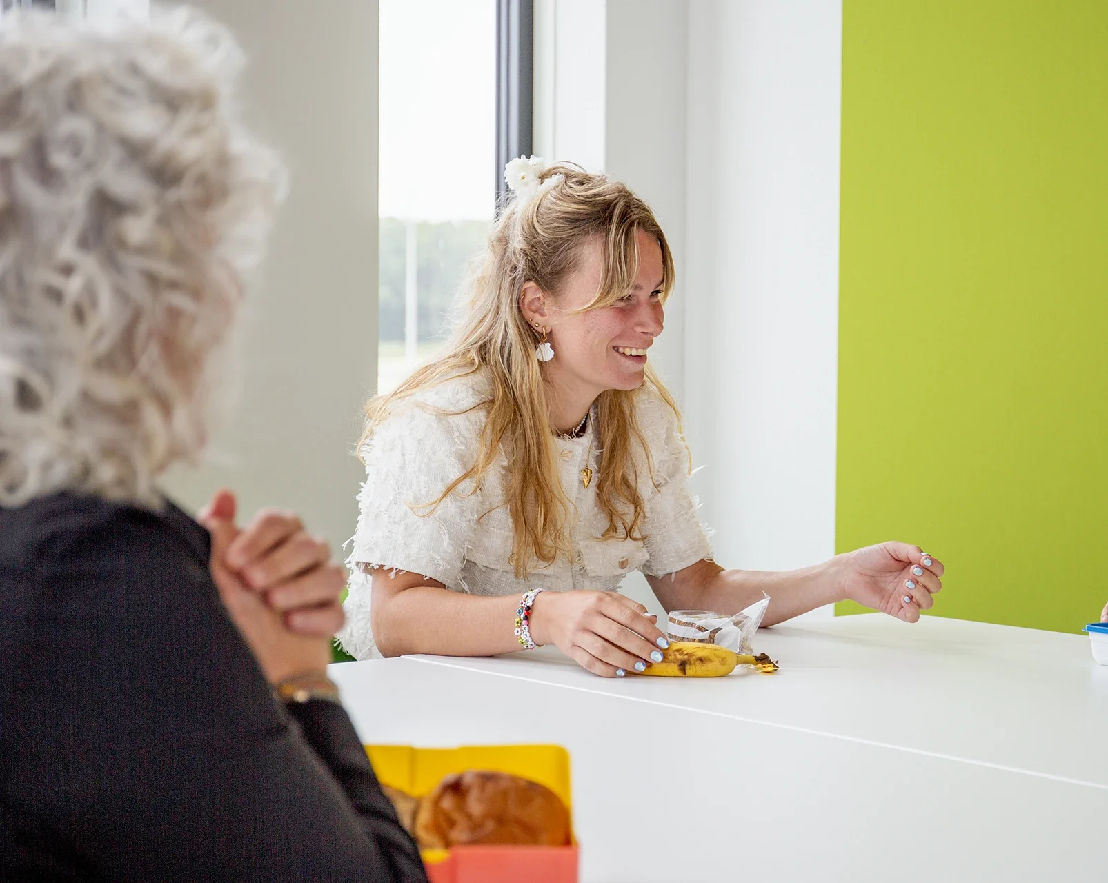 Vrouw lachend aan de lunchtafel met andere collega's naast haar