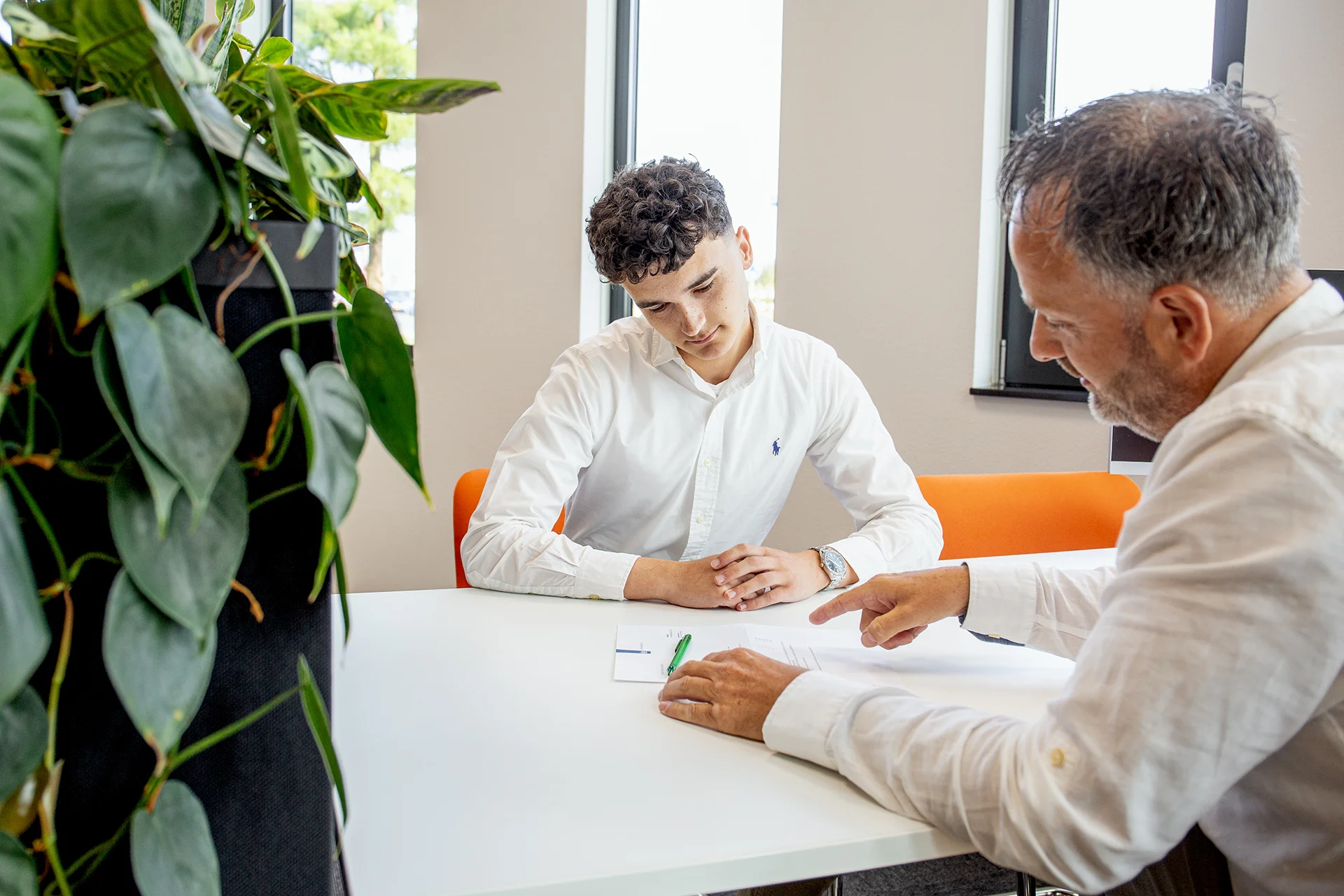 Sander helpt een stagiaire met uitleg over een schoolproject